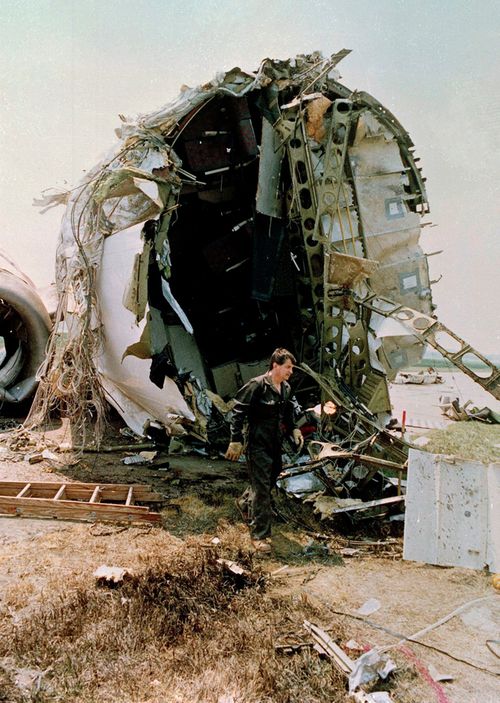 A National Transportation Safety Board investigator walks in front of the torn portion of the passenger compartment of the United Airlines DC-10 that crashed and exploded on landing at Sioux Gateway Airport, near Sioux City, Iowa