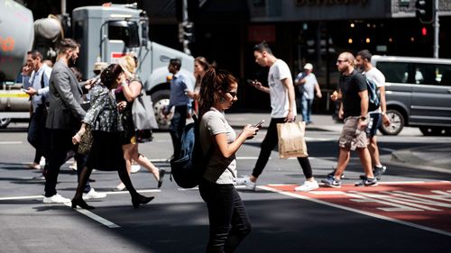 People crossing the road while texting on their phones
