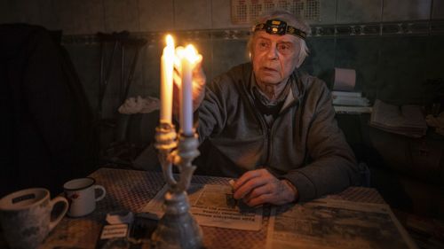 Volodymyr Dubrovsliy, a disabled pensioner, lights candles in his house after living without electricity for more than four months in Kupiansk, Kharkiv region, Ukraine, Wednesday, Dec. 28, 2022.