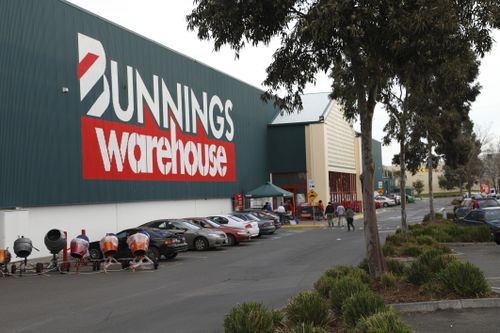 澳大利亚墨尔本 — 2011 年 7 月 23 日：Bunnings 是澳大利亚最成功的五金连锁店。这是墨尔本埃平一家商店的外部。包括步行到入口的顾客和停在附近的汽车。