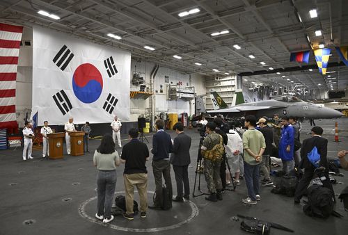 Crew members and member of the media gather in the hanger of the Theodore Roosevelt (CVN 71), a nuclear-powered aircraft carrier, anchored in Busan Naval Base in Busan, South Korea Saturday, June 22, 2024