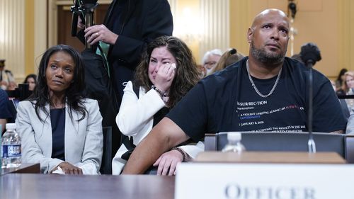 US Capitol Police Sargent Harry Dunn, right, Sandra Garza, the longtime partner of fallen Capitol Police Officer Brian Sicknick, center, and Serena Liebengood, widow of Capitol Police officer Howie Liebengood, left, react as a video of the January 6 attack on the US Capitol is played during a public hearing.