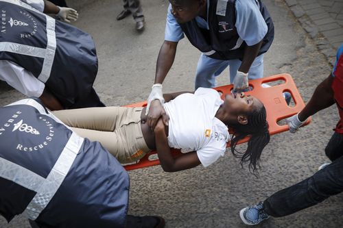 An injured woman is carried away for treatment on a stretcher.