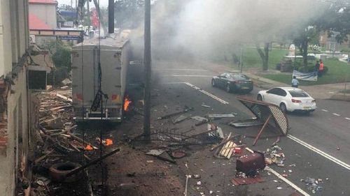 A bus shelter roof is torn off by the truck, which is still on fire. (Dan Irwin/Twitter)