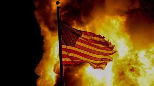 A flag flies over a department of corrections building ablaze during protests in Kenosha, Wisconsin.