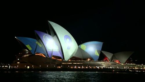 At 7.40pm when the famous sails were first lit up, people lining the building's forecourt also began to shine beams of light from torches onto the images in the hopes of obscuring the message.