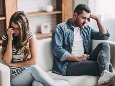 A couple sitting on opposite ends of a couch looking away from each other during a fight