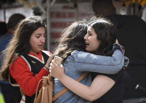 Friends embrace after shots were fired during the Toronto Raptors NBA basketball championship parade (Andrew Lahodynskyj/The Canadian Press via AP)