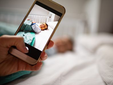 Parent taking photo of a baby with smartphone.