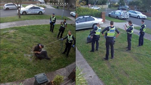 An officer then sprays the man with a watering hose while another draws out his mobile phone to film. (Fairfax Media)