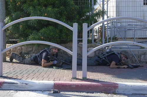 Israeli security forces take cover during rocket attack siren warning as rocket fired from the Gaza Strip, in Ashkelon, southern Israel, Saturday, Oct. 7, 2023.  
