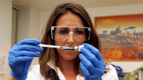 Dr Felicity Hartnell, a clinical research fellow at Oxford University, holds a vial of an experimental vaccine against Ebola. (AAP)