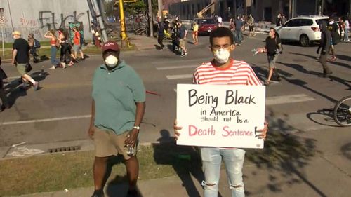 A man holds a sign as riots over the death of George Floyd escalate,