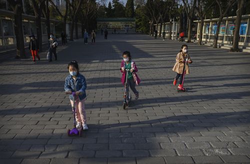 Chinese girls wear protective masks as they ride scooters at Ritan Park on March 22, 2020 in Beijing.