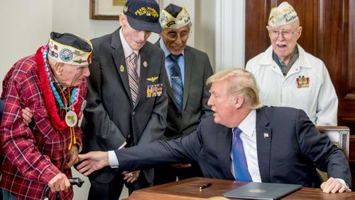 US President Donald Trump speaks with US veteran Lawrence Parry (left), who fought at Pearl Harbor, after signing a proclamation for National Pearl Harbor Remembrance Day at the White House. (AAP)