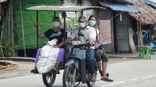 In this July 28, 2021, file photo, people wearing face masks to help curb the spread of the coronavirus ride a tricycle to transport goods in Shwe Pyi Thar township in Yangon, Myanmar.