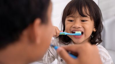 happy kid and dad having fun while brushing their teeth together in the bathroom sink