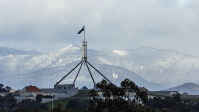 Parliament House in the foreground with snow on the mountains surrounding the ACT, in Canberra on Wednesday, June 1, 2022