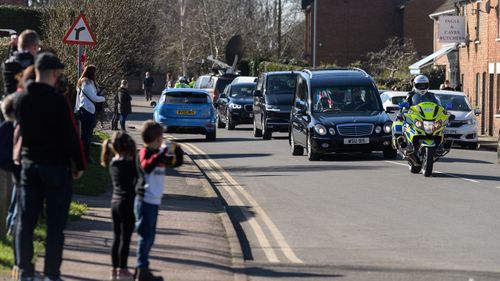 The funeral procession for Sir Tom Moore passes through the village of Marston Moretaine on the way to Bedford Crematorium ahead of a private ceremony on February 27, 2021 in Bedford, England