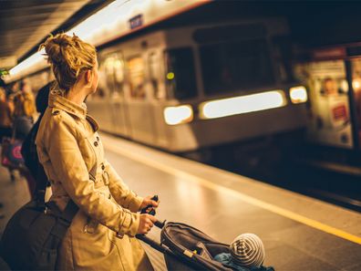 Mother holding onto stroller while waiting for train.