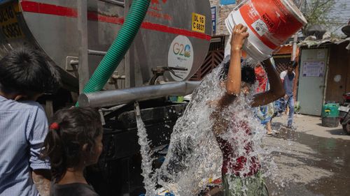 A boy cools himself with potable water from the New Delhi Municipal Council water tanker on May 02, 2024 in New Delhi, India. 
