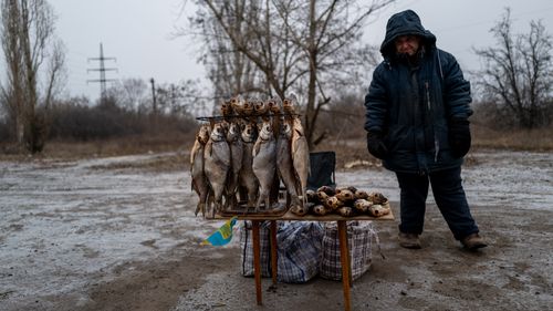 A man sells dried fish along a street near the Bakhmut front lines with Russia on January 22, 2023 in Chasov Yar, Ukraine. 