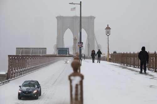 Motoristas e pedestres cruzam a Ponte do Brooklyn durante uma tempestade de inverno, domingo, 25 de janeiro de 2026, em Nova York.  