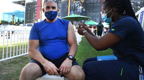 Football fan Geoff Cox receives the Pfizer COVID-19 vaccine at a pop-up clinic. 