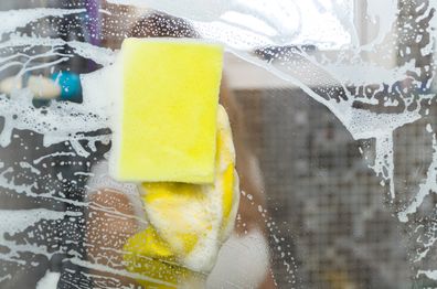 cleaning shower glass with soapy water and a sponge