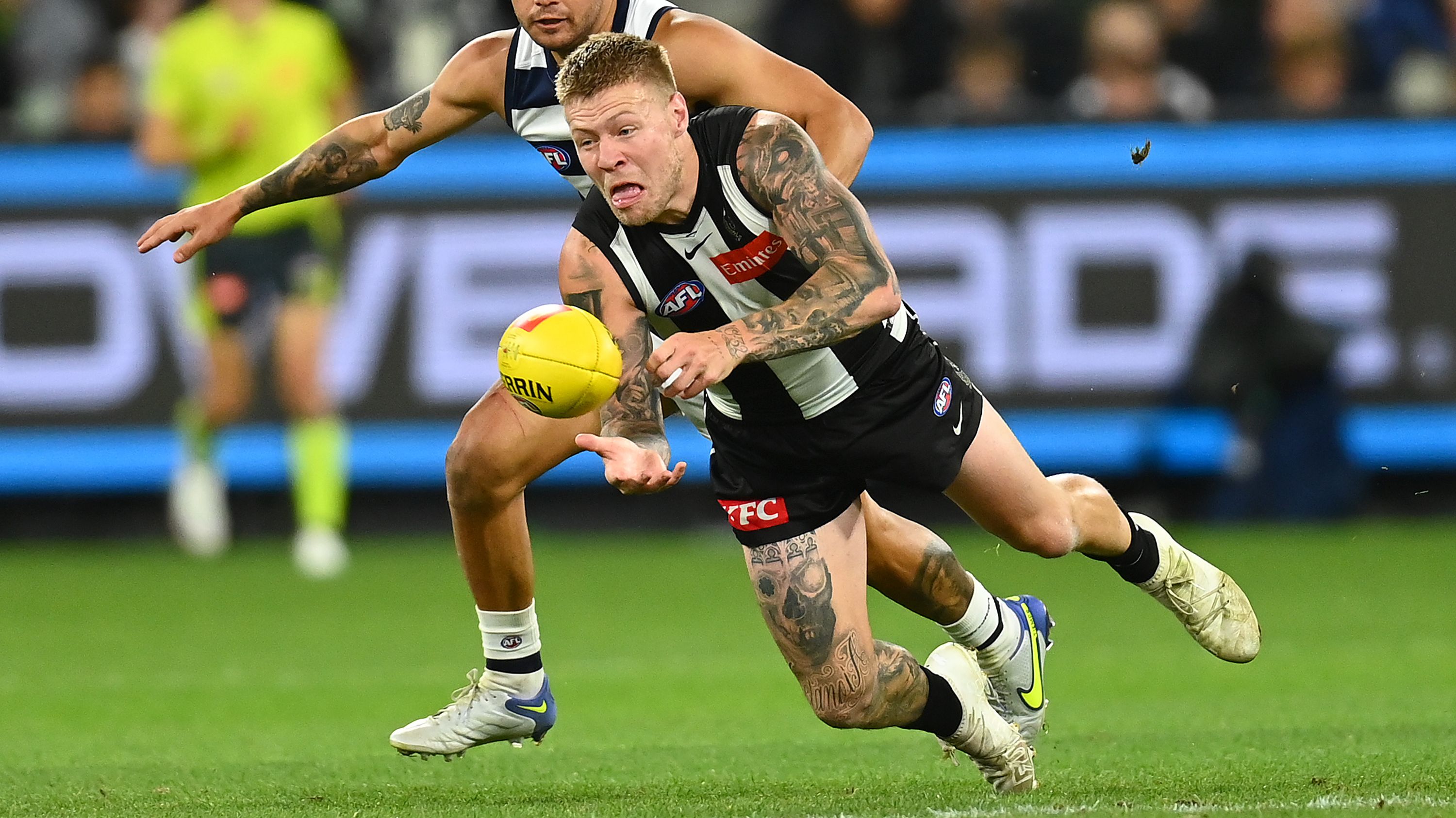 Collingwood&#x27;s Jordan De Goey handballs whilst being tackled  by Geelong&#x27;s Brandan Parfitt.