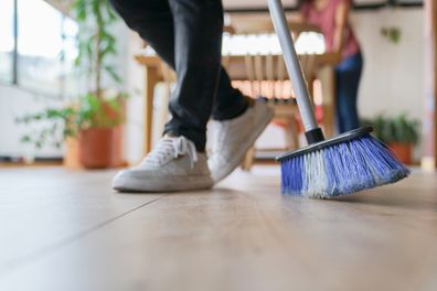 Close-up on a couple cleaning their home and sweeping  domestic chores concepts