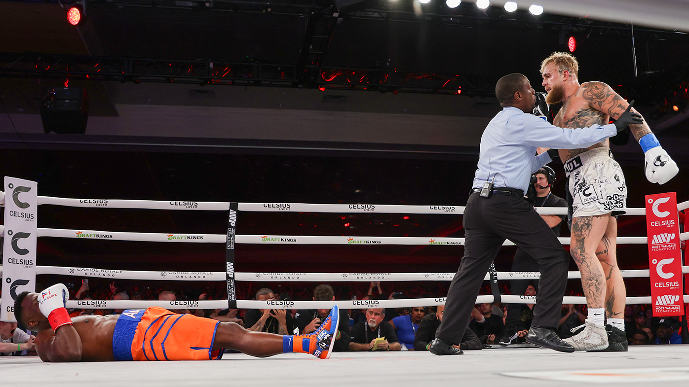 Referee Christoper Young holds back Jake Paul after he knocks out Andre August.