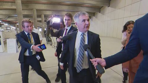 Optus CEO Stephen Rue, surrounded cameras and journalists ahead of his meeting with Anika Wells in Parliament House. 
