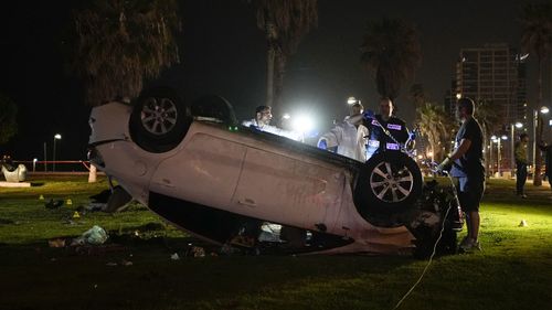 Israeli police stand around a car involved in an attack in Tel Aviv, Israel. Police said a car rammed into a group of people near a popular seaside park before flipping over.