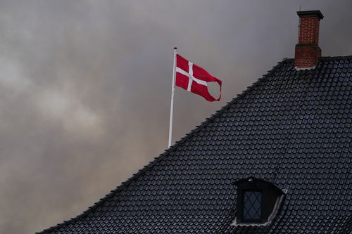 Smoke surrounds the Danish flag above the Ministry of Finance as the Old Stock Exchange, not in the picture, burns, in Copenhagen, Denmark, Tuesday, April 16, 2024. 