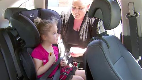 Vicky Ryding puts daughter Eliza into her car seat. (9NEWS)