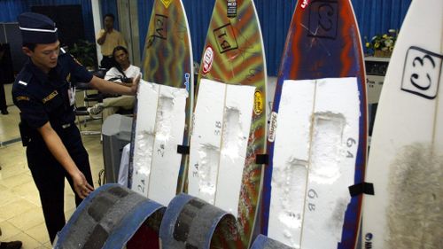 A customs officer inspects surfing boards used by Brazil's citizen Rodrigo Gularte to smuggle six kilograms of cocaine. (AAP)