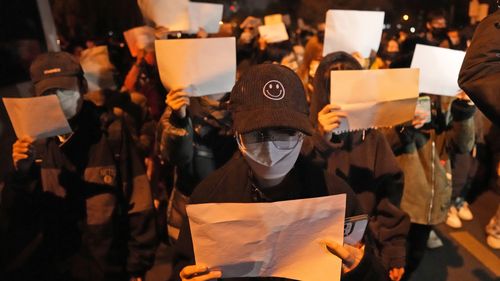 Protesters hold up blank papers and chant slogans as they march in protest in Beijing.