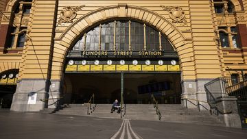 A lone person reads a newspaper at Flinders Street Station in Melbourne.