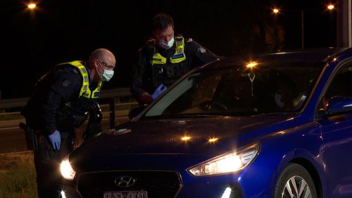 Police check cars trying to cross the Victorian border at Albury before the midnight closure.