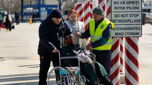 Ukrainian refugees are helped across the border into Moldova.