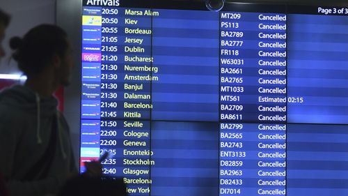 People look at the arrivals board at Gatwick airport, as the airport remains closed after drones were spotted over the airfield.