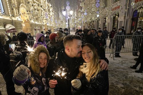 People celebrate the New Year in Nikolskaya street near an empty Red Square due to pandemic restrictions during New Year celebrations in Moscow, Russia, Saturday, Jan. 1, 2022