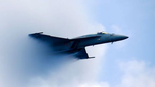 An F/A-18 Super Hornet fighter jet flies through the sky.