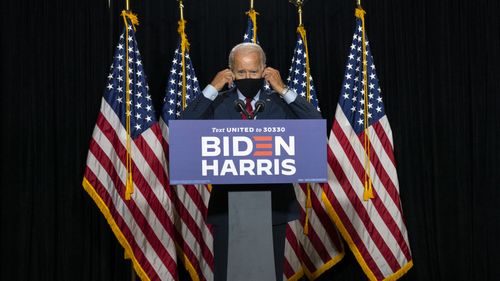 Democratic presidential candidate former Vice President Joe Biden removes his face mask as he arrives to speak at the Hotel DuPont in Wilmington, Del., Thursday, Aug. 13, 2020.