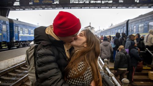 A couple kiss while waiting at Lviv-Holovnyi railway station in Lviv, Ukraine, with men forced to stay an fight.