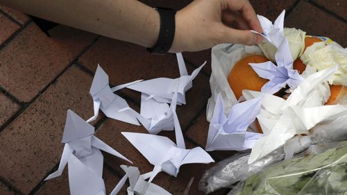 A mourner places paper birds near the flowers on the site where a man fell to his death a day earlier after hanging a protest banner on the scaffolding of a shopping mall in Hong Kong.