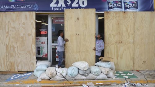 Lavoratori sorvegliano un negozio di alimentari dall'uragano Milton, a Progreso, Yucatán, Messico.