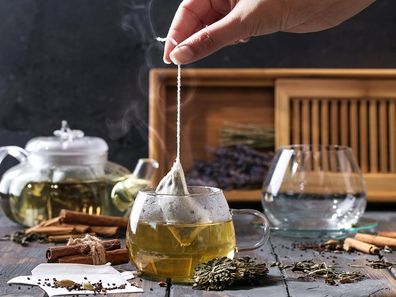 Woman dipping a tea bag into hot water.