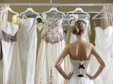 Bride standing in front of wedding dresses